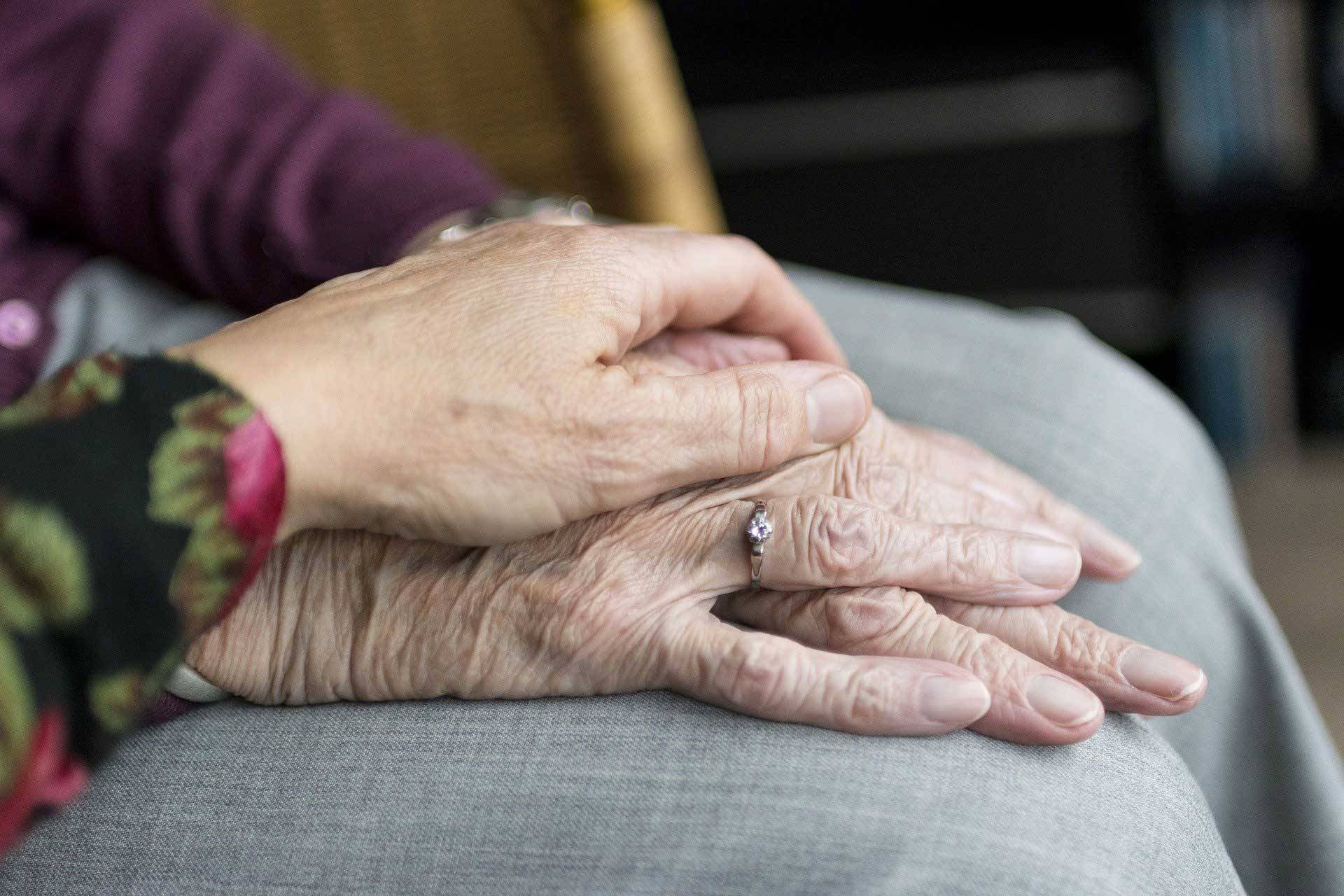 Hände von alten Menschen greifen ineinander